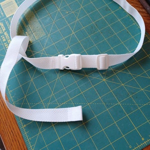 Puede incluir: Un cintur&oacute;n de correa tejida blanca con una hebilla de pl&aacute;stico de liberaci&oacute;n lateral y una hebilla deslizante ajustable. El cintur&oacute;n est&aacute; fabricado con un material de tela texturizada duradera e incluye un extremo suelto para el ajuste.
