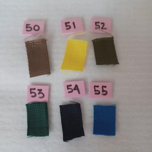 Puede incluir: Seis muestras de tela rectangulares en marr&oacute;n, amarillo, verde oliva, verde oscuro, negro y azul. Cada muestra est&aacute; emparejada con una peque&ntilde;a etiqueta de papel rosa etiquetada con los n&uacute;meros 50, 51, 52, 53, 54 y 55 en tinta negra.