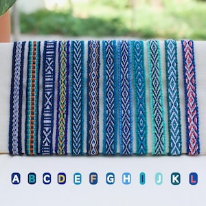May include: A selection of woven fabric bracelets in shades of blue, teal, and white. Each bracelet has a unique geometric pattern. The bracelets are displayed together, showcasing the different designs.