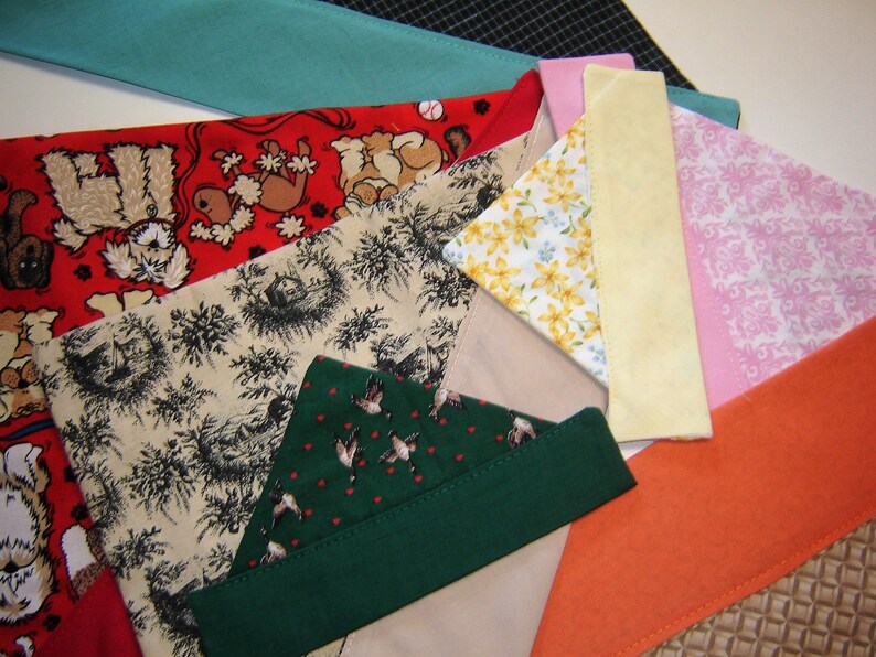 May include: Assortment of fabric scraps in various patterns and colors, including red with dog illustrations, beige with a floral pattern, green with a bird pattern, yellow, pink with a damask pattern, and orange.