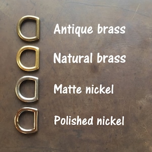 May include: Four metal D-rings in different finishes: antique brass, natural brass, matte nickel, and polished nickel.