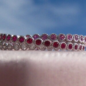 Bague à rouler en or blanc avec rubis, saphirs roses et diamants dans un cadre millegrain, anneau triple entrelacé, bague Trinity, alliance