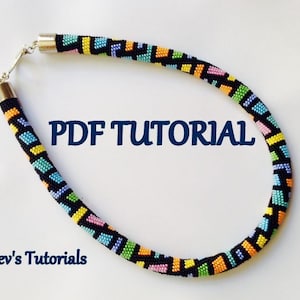Op de afbeelding: Een kleurrijke kralenketting met een geometrisch patroon. De ketting is gemaakt met zwarte, gele, oranje, groene, blauwe en roze kralen. De ketting heeft aan beide uiteinden zilveren sluitingen. De tekst "PDF TUTORIAL" is in blauwe letters op een witte achtergrond geschreven. De tekst "Alev's Tutorials" is in blauwe letters op een witte achtergrond geschreven.