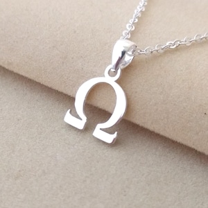 Peut inclure: Un collier en argent avec un pendentif en forme de symbole oméga.