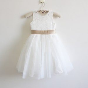 May include: White tulle dress with a lace bodice and a gold satin sash.