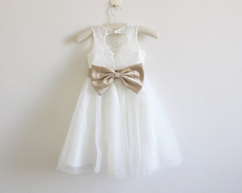 May include: White tulle dress with a lace bodice and a gold satin bow.