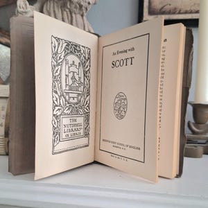 May include: An open vintage book titled "An Evening with Scott" with the text "The Nutshell Library" and a decorative illustration. The book is on a white surface, with a statue in the background.