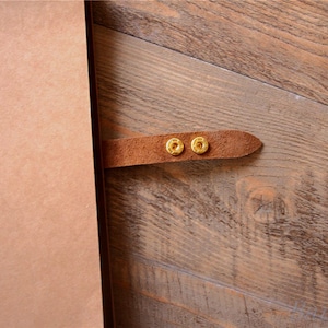 May include: A brown leather journal with a brown leather strap and two gold metal clasps.