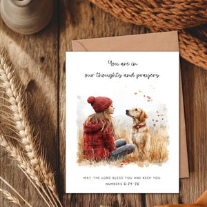 May include: A greeting card with a watercolor illustration of a person and a dog. The card has the text "You are in our thoughts and prayers." and "May the Lord bless you and keep you. Numbers 6:24-26."