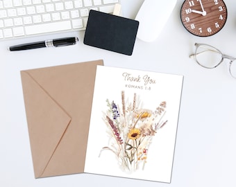 Peut inclure: Une carte blanche avec un bouquet de fleurs séchées et le texte "Thank You" et "Romans 1:8" en lettres dorées. La carte est sur une enveloppe brune.