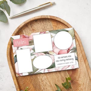 May include: A floral-themed notepad with blank spaces for notes and a quote from Lamentations 3:23. The notepad features pink and green watercolor flowers and the word "Notes" in a pink box. A silver pen rests on a wooden tray.