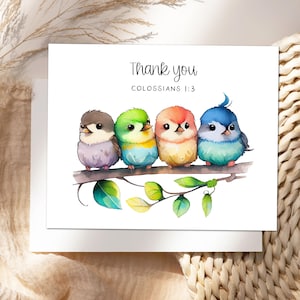 May include: A white greeting card featuring the text Thank you and COLOSSIANS 1:3 above a watercolor illustration of four small, colorful birds perched on a brown tree branch with green leaves. The birds are purple, green, orange, and blue.