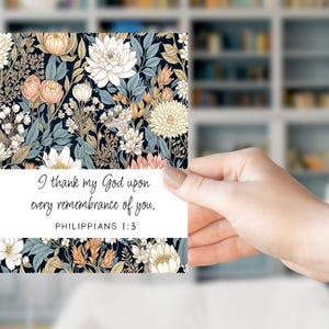 May include: A floral print card featuring a dark background with cream, peach, and blue flowers. The card has the text "I thank my God upon every remembrance of you. Philippians 1:3."