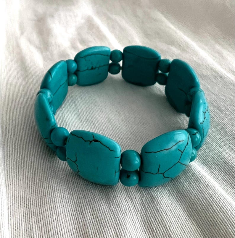 May include: A turquoise blue stretchy bracelet made of square-shaped beads.