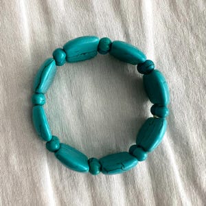 May include: A turquoise beaded bracelet with oval-shaped beads.