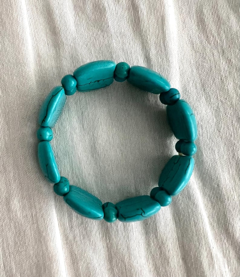 May include: A turquoise beaded bracelet with oval-shaped beads.