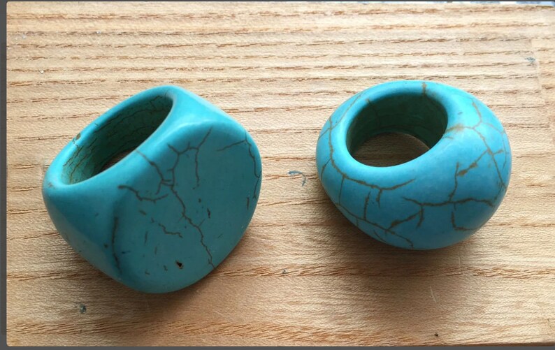 May include: Two turquoise rings made of stone with a crackled finish. The rings are different shapes, one is round and the other is oval.