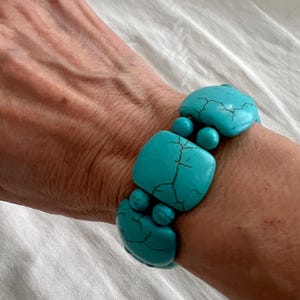 May include: A turquoise blue bracelet made of square and round beads. The bracelet is made of natural stone and has a rustic look.