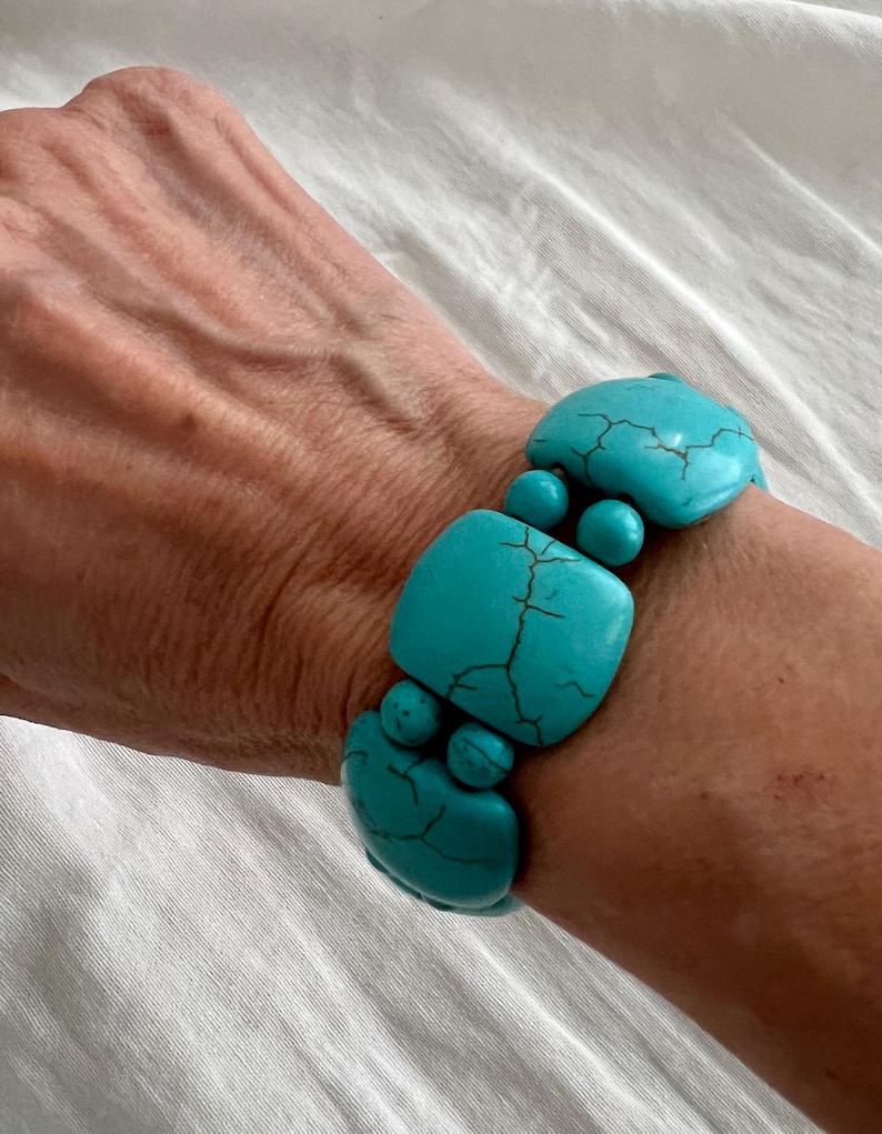 May include: A turquoise blue bracelet made of square and round beads. The bracelet is made of natural stone and has a rustic look.
