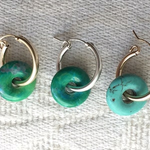 May include: Three pairs of hoop earrings with turquoise and green stone accents. The hoops are made of gold and silver metal.