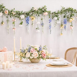 Pu&ograve; includere: Una tavola splendidamente decorata con un centrotavola floreale, candele e foto incorniciate. Sopra, una ghirlanda di fiori e verde pende contro un muro bianco. La tavola &egrave; apparecchiata per un'occasione speciale.