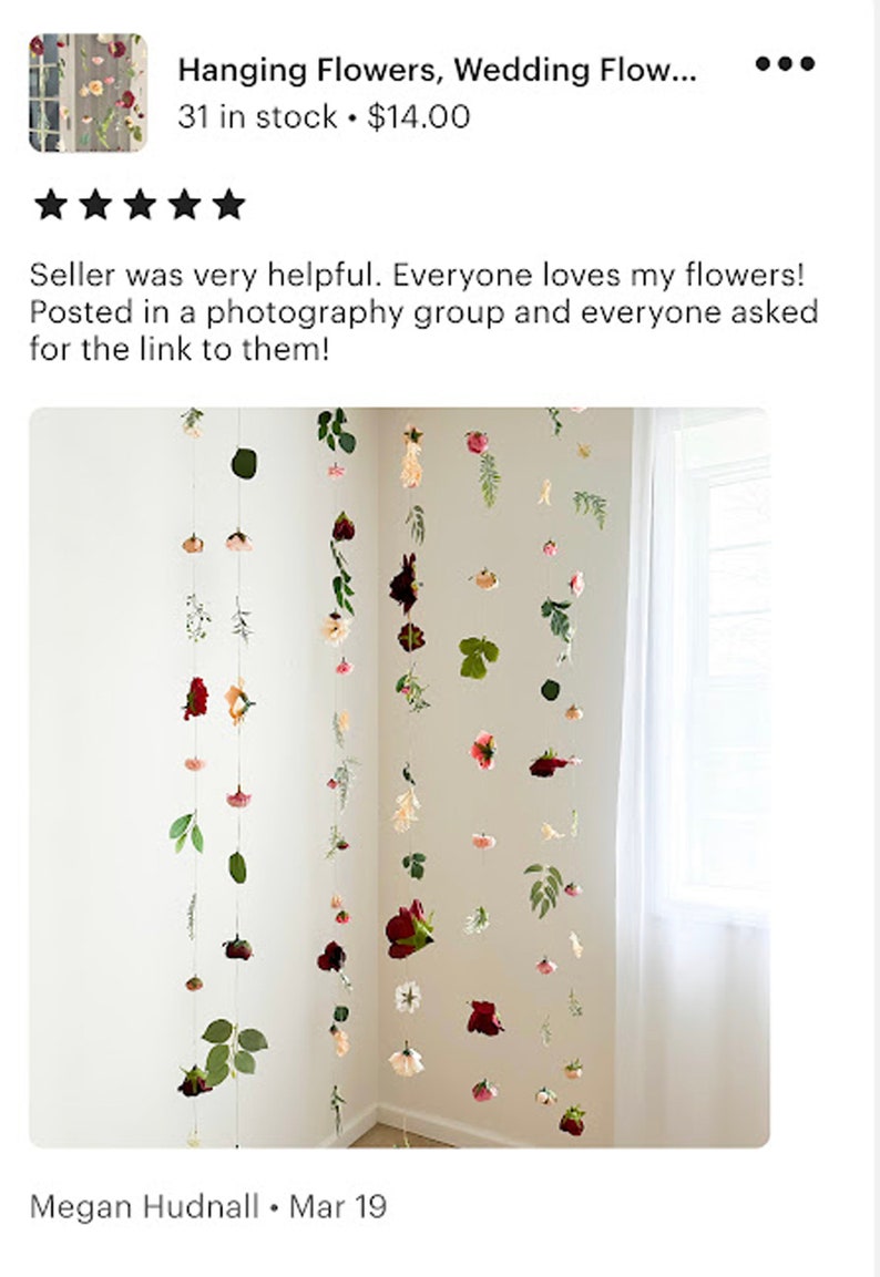 May include: Multiple vertical strands of hanging flowers and green leaves suspended from above. The arrangement features various floral blooms in shades of red, pink, white, and cream, interspersed with green foliage along thin, clear strings.