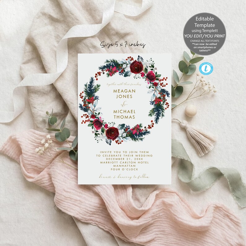 May include: A 5 by 7 inch wedding invitation card featuring a central wreath of dark red roses, pine needles, and red berries. The text reads Meagan Jones and Michael Thomas, invite you to join them to celebrate their wedding December 21, 20XX.