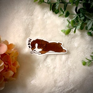 May include: A brown and white cartoon puppy with the word "zzz" above it, sleeping on its side. The puppy is on a white background.