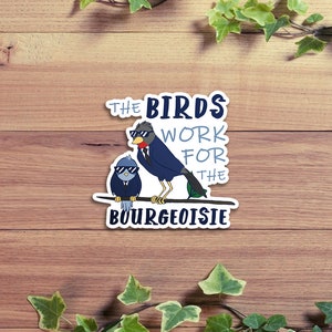 Puede incluir: Una pegatina con dos pájaros de dibujos animados que llevan gafas de sol y trajes. El texto de la pegatina dice "The Birds Work For The Bourgeoisie".