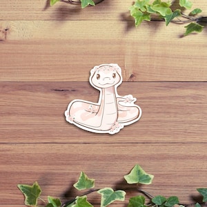 May include: A pink snake with a flower crown on a wooden background with green ivy.