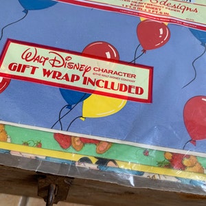 May include: A pack of Walt Disney character gift wrap featuring balloons and a blue background. The pack includes 12 sheets of wrapping paper, each measuring 1 foot 8 inches by 2 feet 6 inches, for a total of 50 square feet. The price is &pound;1.73.
