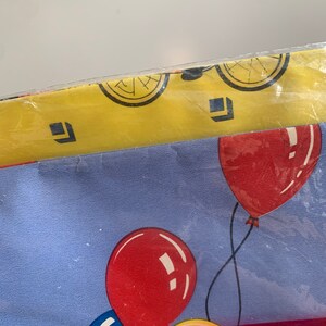 May include: A blue and yellow tablecloth with a red, blue, and yellow balloon pattern. The tablecloth has a Kmart price tag that says "&pound;1.73".