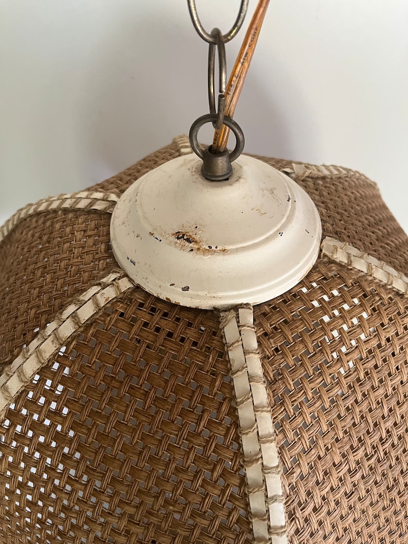 Puede incluir: Una l&aacute;mpara colgante tejida de color blanco y marr&oacute;n con una placa de techo de metal blanco y una cadena colgando.