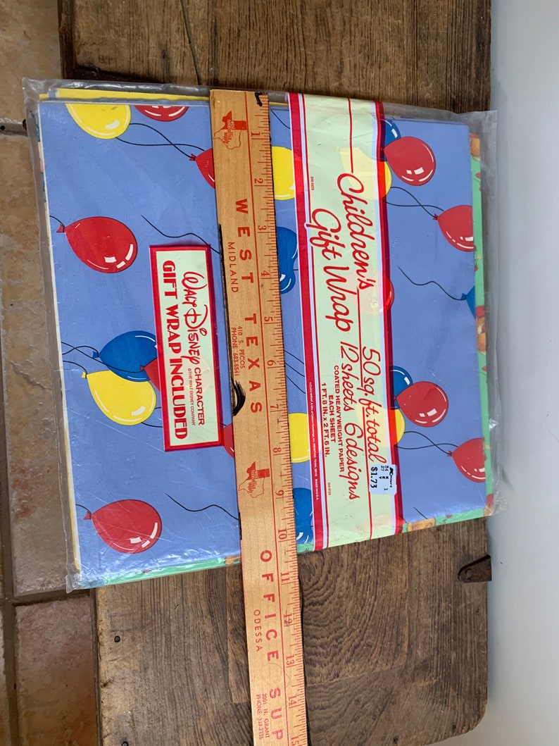 May include: A pack of 12 sheets of Children's Gift Wrap featuring a blue background with red, yellow, and blue balloons. The pack states that it contains 50 square feet of gift wrap and is priced at &pound;1.73. The text "WALT DISNEY CHARACTER GIFT WRAP INCLUDED" is printed on the pack.
