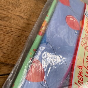 May include: A pack of wrapping paper with a blue background and red balloons. The text on the pack says "50 sq ft.  Birthday Wrap".