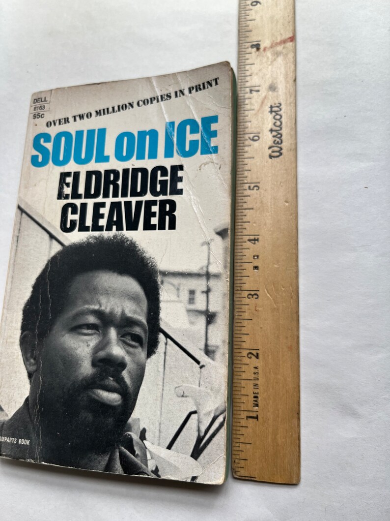 May include: A vintage paperback book cover with a black and white photo of a man with a beard. The title of the book is "Soul on Ice" by Eldridge Cleaver. The cover is blue, white, and black.
