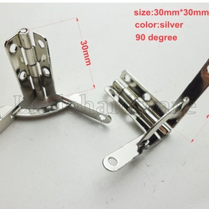 Può includere: Due cerniere angolari argentate a 90 gradi. Ogni cerniera misura 30 mm x 30 mm. L'immagine include il testo che indica le dimensioni, il colore e l'angolo delle cerniere. Le cerniere hanno più fori per viti per un montaggio sicuro.