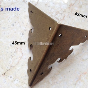 May include: Brass corner bracket with a decorative design. The bracket measures 4.5 inches by 4.2 inches.