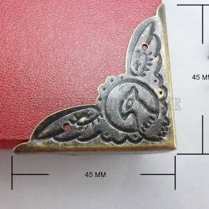 May include: Antique brass corner protectors with a decorative floral design. Each corner protector measures 45 mm in size.