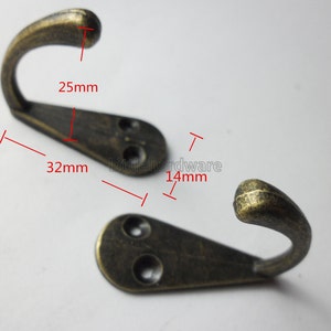 Könnte beinhalten: Zwei antike goldfarbene Metallhaken mit abgerundeter Hakenform und zwei Löchern auf der Rückseite zur Montage. Der Haken ist 8,1 cm lang und 2,5 cm breit.