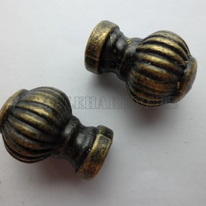May include: Two round cabinet knobs with a ribbed, pumpkin-like texture and a dark, distressed antique brass finish. Each knob features a central stem and a flat circular base, displaying a weathered metallic appearance with dark recessed areas.