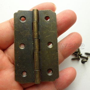 Può includere: Cerniere in ottone antico con finitura anticata e un set di viti. Le cerniere sono lunghe 2,5 cm.