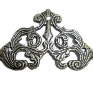 Puede incluir: Escuadra de esquina de metal ornamentada, de estilo antiguo, con acabado bronce. La pieza decorativa presenta diseños florales y de hojas en espiral, con un elemento central puntiagudo y múltiples orificios para tornillos para el montaje. Ideal para muebles o proyectos de artesanía.
