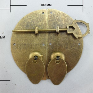 May include: A brass door latch with a keyhole and a round handle. The latch is 10 cm in diameter.