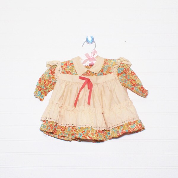 Vintage baby dress. multi-color floral under long sleeve dress with beige pinafore and bow detailing, no name sz for 3-6 Mo