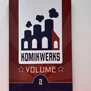 May include: A red, white, and blue book with a factory illustration and the text "KOMIKWERKS VOLUME 2".