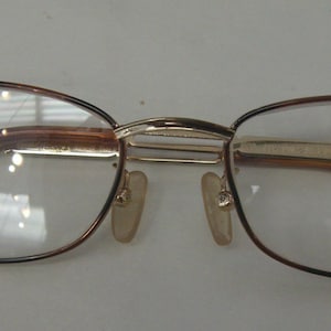 May include: Brown and gold eyeglasses with a rectangular frame and clear lenses.
