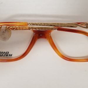 Puede incluir: Gafas de pasta de carey marrón con patillas de metal dorado y un logotipo de Versace Gianni en el lateral.