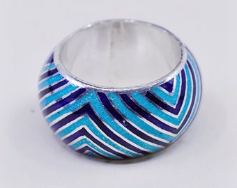 Puede incluir: Un anillo de plata con una banda ancha, con un patrón de chevron en tonos de esmalte azul y blanco. El anillo tiene un interior de plata pulida y un diseño geométrico audaz. Este anillo llamativo es una joya.