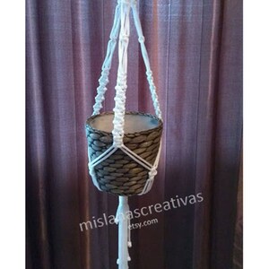 May include: White macrame plant hanger with a brown woven pot. The hanger has a long tassel at the bottom. The text "mislanascreativas etsy.com" is visible in the bottom right corner of the image.